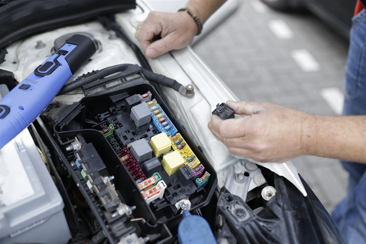 Técnico testando a caixa de fusíveis de um carro