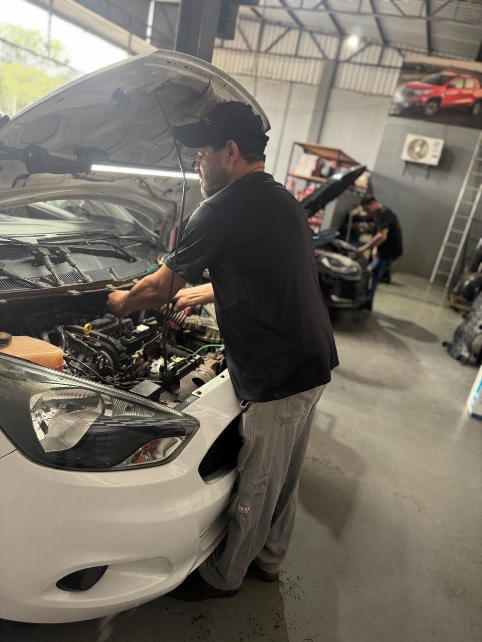 Mecânico da Eletrocar trabalhando no motor de um carro na oficina